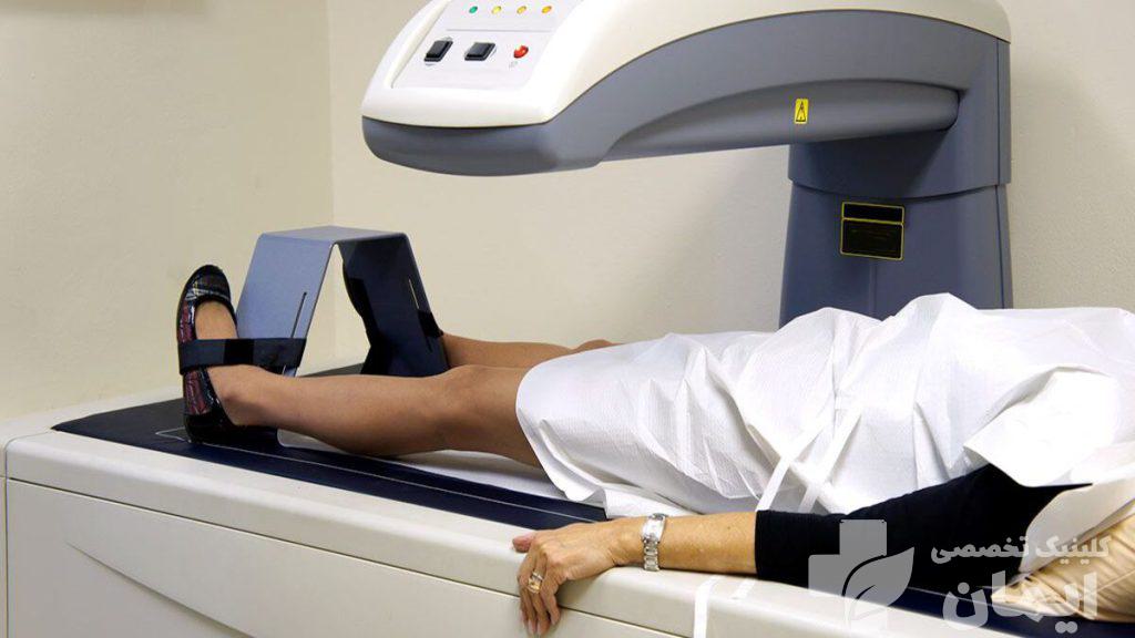 انجام آزمایش تراکم استخوان برای بیمار بیمار روی تخت خوابیده و آزمایش تراکم استخوان انجام می دهد
