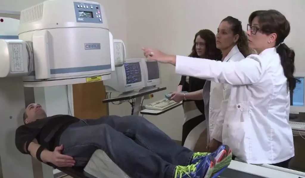 اقای بیماری که شکستگی پنهان دارد اسکن استخوان انجام میدهد اقای بیماری که شکستگی پنهان دارد اسکن استخوان انجام میدهد