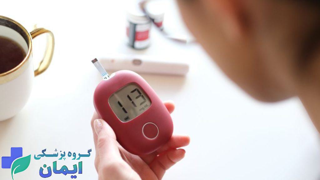 دستگاه تست قند خون فردی که در حال خواند جواب گلوکومتر قرمز رنگ در دستانش می باشد